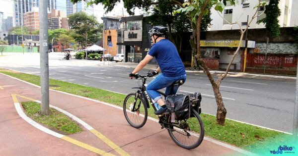Ciclista pedalando em ciclovia com alforges na bicicleta